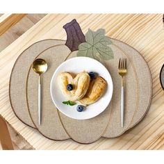 a white plate topped with pastries on top of a wooden table next to silverware