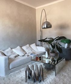 a living room filled with white furniture and lots of pillows on top of a rug