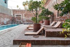 an outdoor patio area with lounge chairs and potted plants next to a swimming pool