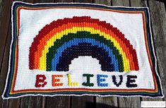 a crocheted pillow that says believe with a rainbow on the front and bottom