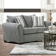 a living room scene with focus on the sofa and chair, coffee table and lamp