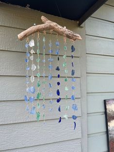 a wind chime hanging on the side of a house with blue and green glass beads