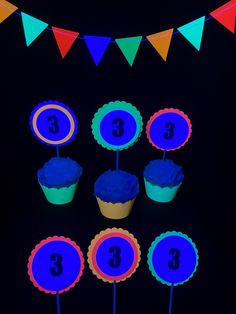 cupcakes with blue frosting and numbers on them are lit up in the dark