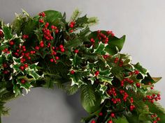 a wreath with holly and red berries hanging from it's sides on a wall