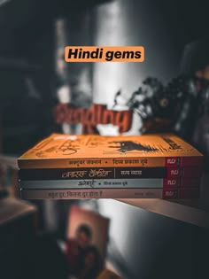 three books stacked on top of each other in front of a table with an orange sign that reads, hindu gems