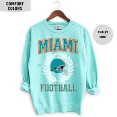 Perfect sweatshirt for Miami football fans this season! Ideal for any situation, a unisex heavy blend crewneck sweatshirt is pure comfort. These garments are made from polyester and cotton. This combination helps designs come out looking fresh and beautiful. The collar is ribbed knit, so it retains its shape even after washing. There are no itchy side seams on these sweaters.  .: 50% cotton, 50% polyester .: Medium-heavy fabric (8.0 oz/yd² (271.25 g/m .: Loose fit .: Sewn-in label .: Runs true t Blue Crew Neck Sweatshirt With Team Logo, Pre-shrunk Crew Sweatshirt Fan Apparel, Team Name Crew Neck Sweatshirt For Fan Gear, Sports Fan Sweatshirt With Crew Neck, Pre-shrunk, Crew Neck Sweatshirt With Team Name For Fan Gear, Sports Fan Sweatshirt With Pre-shrunk Crew Neck, Varsity Crew Neck Pre-shrunk Sweatshirt, Crew Sweatshirt For Sports Season, Pre-shrunk Crew Sweatshirt For Sports Season