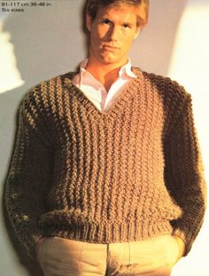 a man in a sweater leaning against a wall