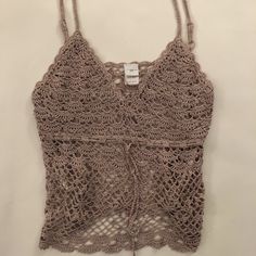 a crocheted tank top hanging on a wall with a tag attached to it