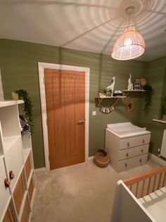 a baby's room with green walls and white dressers in the foreground