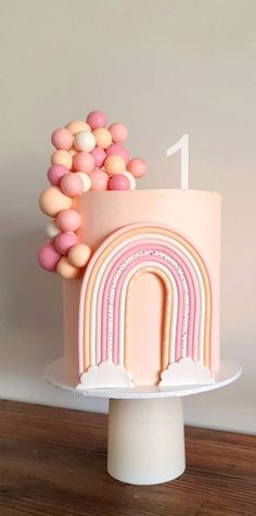 there is a pink cake with a rainbow decoration on the top and white icing