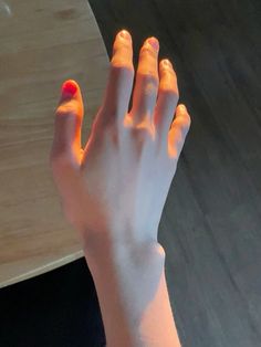 a person's hand with red nail polish on it