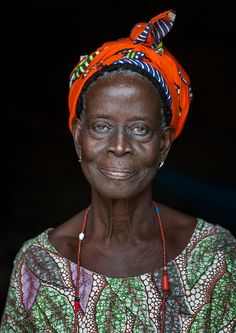 a woman with an orange turban on her head and red beads around her neck