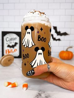 someone holding up a cup with halloween decorations on it