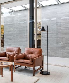 two brown leather chairs sitting next to each other on top of a white carpeted floor