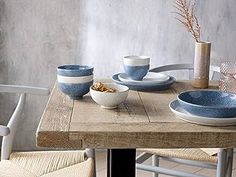 a wooden table topped with plates and bowls