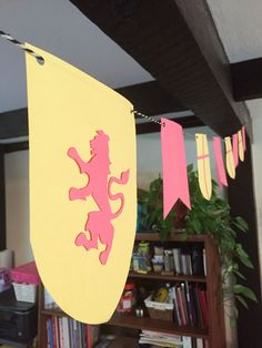 a yellow and pink flag hanging from a ceiling in a room with bookshelves