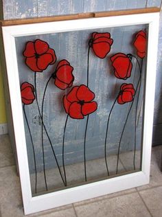 an image of red flowers in a white frame on the floor next to a blue wall