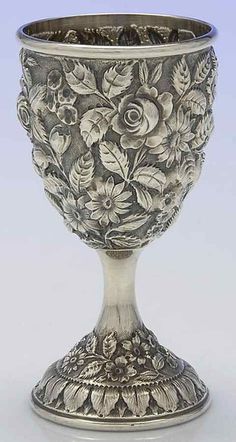 an ornate silver goblet with flowers and leaves