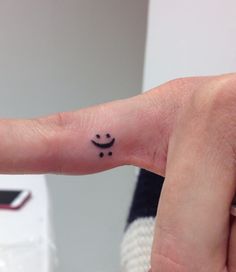 a person with a smiley face tattoo on their finger