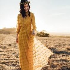 a woman in a yellow dress is walking through the desert with her hand on her hip