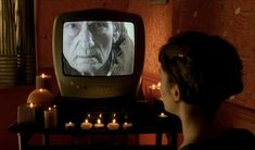 a woman sitting in front of a tv with candles on the table next to it