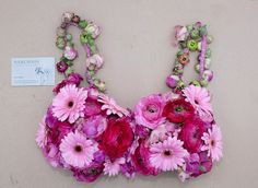 a bra made out of flowers and beads on a wall with a price tag attached to it