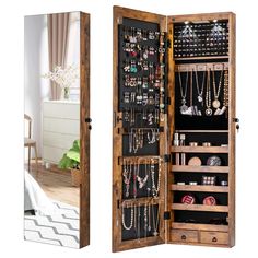 an open wooden jewelry cabinet sitting next to a mirror