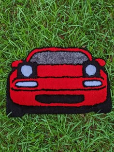 a red car shaped rug sitting on top of green grass