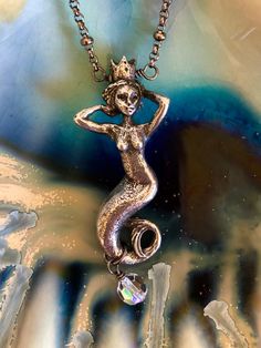 "Known as the Goddess of the Sea this lovely mystical Green Girl Studio pewter mermaid queen is accented with Swarovski crystal on sparkling gunmetal satellite chain. Enchanting mermaid charm with crown is 3D with amazing detail on all sides. Measures 42mm in length. Sparkling 6mm Swarovski Crystal AB round bead is wire wrapped at the bottom. Total drop with crystal is 1 7/8\". Pendant is wire wrapped onto pretty 18\" gunmetal rolo chain with lots of sparkle. Closes with lobster claw clasp and 1 Bohemian Mermaid Necklace For Gifts, Bohemian Mermaid Necklace Gift, Paris Charm Bracelet, Mermaid Queen, Mermaid Pendant Necklace, Goddess Of The Sea, Nautical Necklace, Mermaid Pendant, Girl Necklace