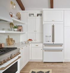 a kitchen with white cabinets and an oven in the center is seen from across the room