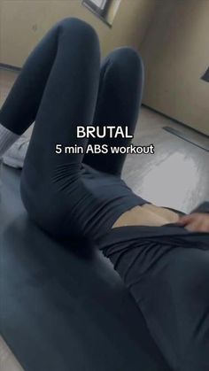 a woman laying on the floor with her legs crossed and wearing black leggings that read brutal 5 min abs workout