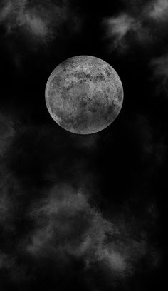 the full moon is seen through clouds in this black and white photo, taken from below