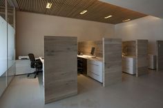 an office with wooden partitions in the middle and white desks on each side