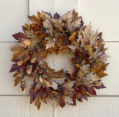 a wreath is hanging on the side of a white door with leaves and acorns