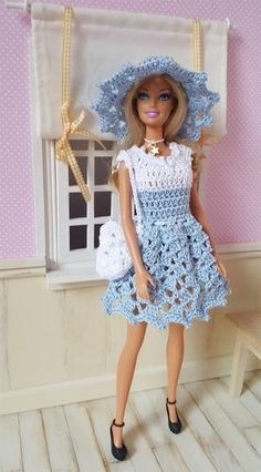 a doll in a blue dress and hat standing next to a window with pink walls