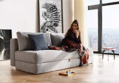 a woman sitting on top of a couch next to a window