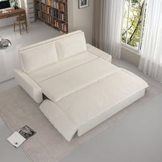 a white couch sitting on top of a rug next to a window