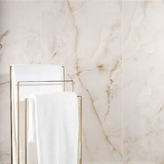 two white towels are sitting next to each other in front of a marble tile wall