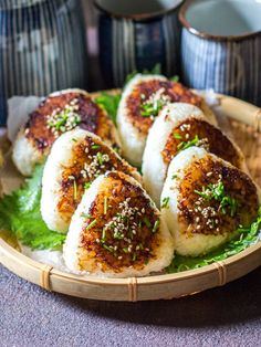 some kind of food on a plate with chopsticks and cups in the background