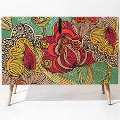 an artistically designed cabinet with two legs and handles on each side, decorated with colorful flowers