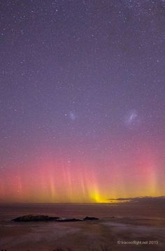 the aurora lights shine brightly in the night sky over an island and body of water