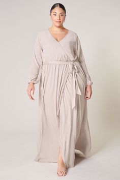 Warm and inviting, the Wholehearted Maxi Dress is a perfect combination of modest and sultry. Long balloon sleeves frame a surplice neckline separated by a tie at the waist, creating a forgiving faux wrap. The skirt maintains an airy and flowy shape that trails behind as you walk down the aisle. - Chiffon- Faux wrap- Keyhole- Elastic waist- Comes in 14 ColorsSize + Fit - Model is 5'9" and wearing size 2X- Measurements taken from size 2X - Chest: 36 1/2"- Length: 66" Fabric Self: 100% PolyesterLi Flowy Wrap Dress For Date Night, Flowy Belted Wrap Dress With Surplice Neckline, Flowy Faux Wrap Maxi Dress, Flowy Faux Wrap Dress With Surplice Neckline, Flowy Wrap Dress With Faux Wrap And Surplice Neckline, Flowy Faux Wrap Dress, Formal Flowy V-neck Wrap Dress, Flowy Faux Wrap V-neck Maxi Dress, Formal Flowy Wrap Dress With Surplice Neckline