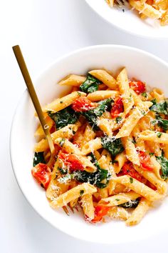 two white bowls filled with pasta and spinach