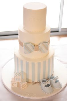 a three tiered cake with baby shoes on top