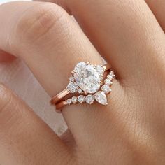 a woman's hand with a rose gold ring and two diamond engagement rings on it