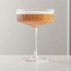 a glass filled with liquid sitting on top of a white counter next to a wall