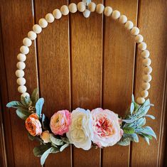 a wreath made out of beads and flowers on a wooden door with a beaded necklace hanging from the front