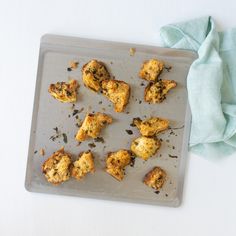 several pieces of chicken on a baking sheet with a blue cloth next to it and a napkin