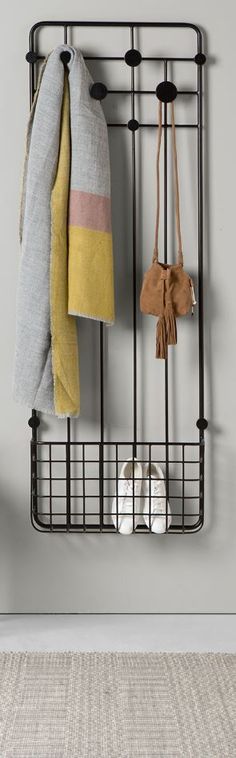 an iron rack with two pairs of shoes and towels hanging on the wall next to it