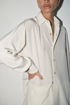 Oversized and relaxed fit. Shirt Collar Curved front and back hem. Back of the shirt fits longer than the front. Exposed Buttons. Mother pearl buttons. French seam finish Fits comfortably across shoulders, falls loose throughout the body. Oversized full-length sleeves with pleats and mother pearl button cuffs. Full-length sleeves with pleats and button cuffs Colour: Nata (Cream) One Size fits S/M/L Model is 1´82 - 5’10" Unisex 100% Pure Silk. Crepe de ChineMADE IN SPAIN French Seam, Shirt Fits, Mother Pearl, Pearl Buttons, Silk Crepe, Shirt Collar, Pure Silk, Length Sleeve, Full Length